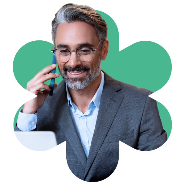 Un homme en costume et lunettes parle au téléphone, représentant Bullhorn Automation pour les solutions d'agence de recrutement.