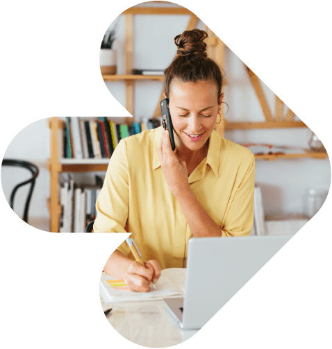 woman on the phone taking notes in her home office